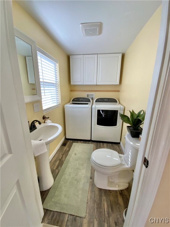 bathroom with hardwood / wood-style floors, toilet, and washer and dryer