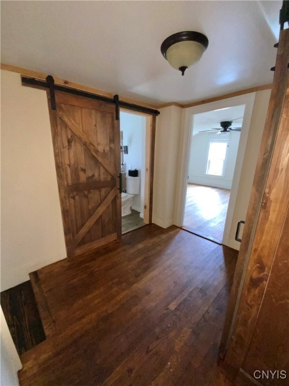 corridor featuring dark wood-type flooring and a barn door