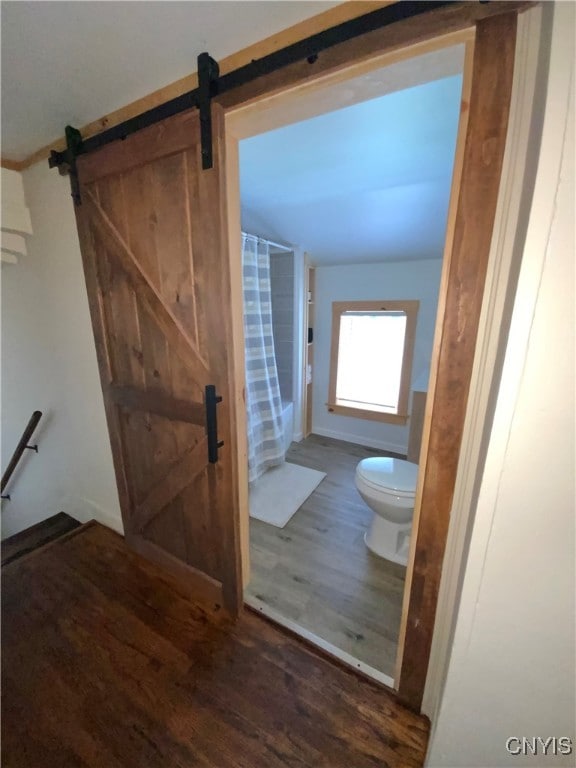 interior space with a barn door and dark hardwood / wood-style flooring