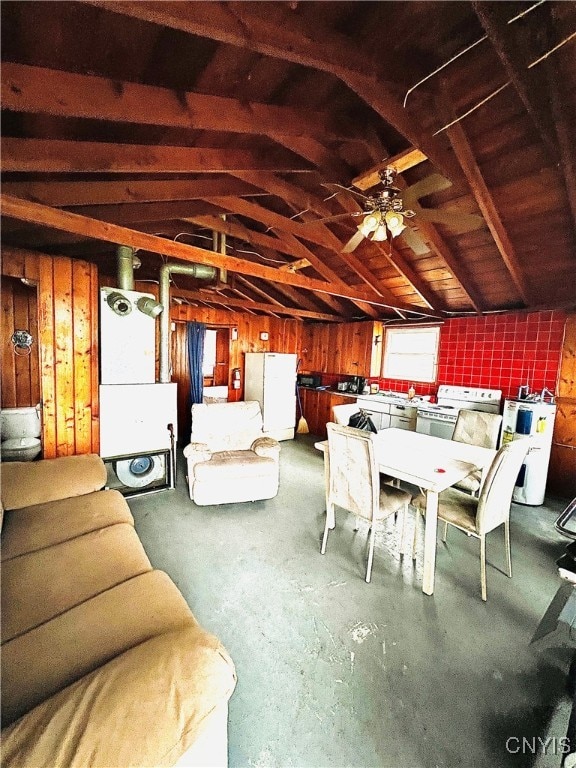 dining space featuring ceiling fan, lofted ceiling with beams, wood walls, and concrete floors