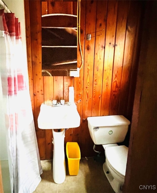 bathroom featuring wooden walls and toilet