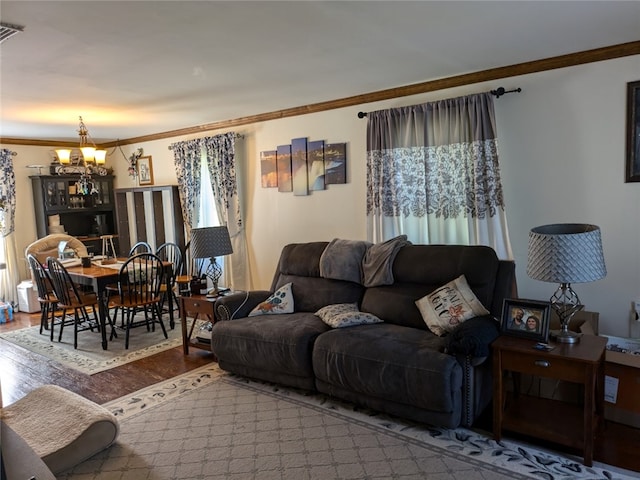 living room with plenty of natural light, crown molding, a notable chandelier, and wood-type flooring