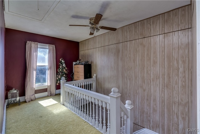 carpeted bedroom featuring ceiling fan, wood walls, and a crib