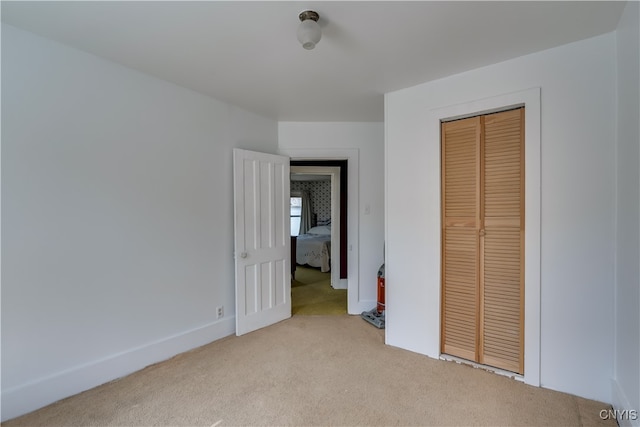 unfurnished bedroom with light carpet and a closet