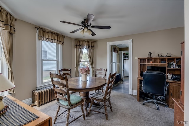 carpeted dining room featuring ceiling fan and radiator