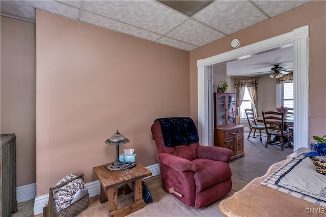 sitting room with carpet, ceiling fan, a paneled ceiling, and radiator heating unit