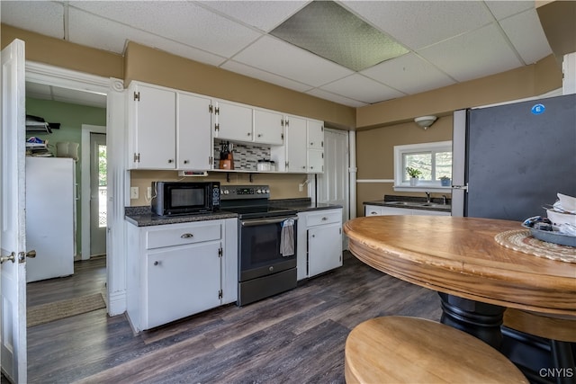 kitchen featuring dark hardwood / wood-style flooring, stainless steel appliances, sink, white cabinets, and a drop ceiling