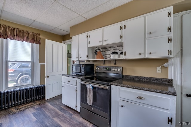 kitchen featuring stainless steel electric range oven, white cabinets, a drop ceiling, dark wood-type flooring, and radiator heating unit