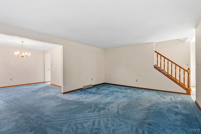 carpeted spare room with a chandelier