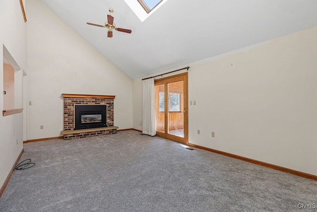 unfurnished living room featuring a skylight, a brick fireplace, carpet flooring, ceiling fan, and high vaulted ceiling