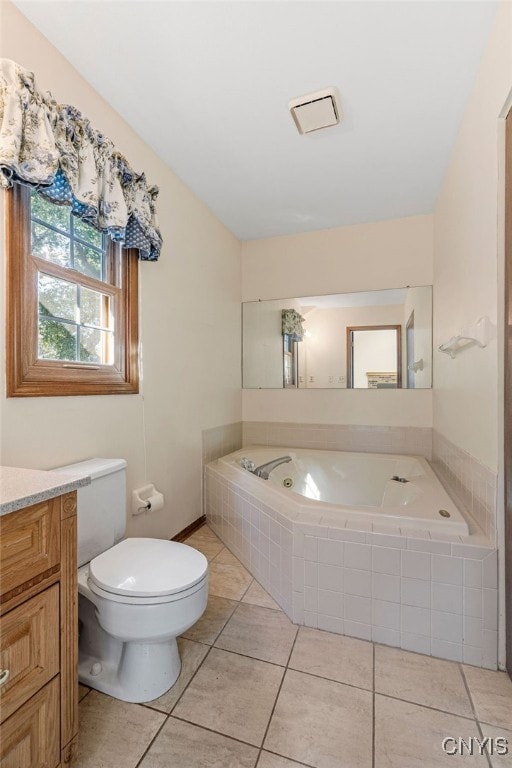 bathroom with tile patterned flooring, tiled bath, toilet, and vanity