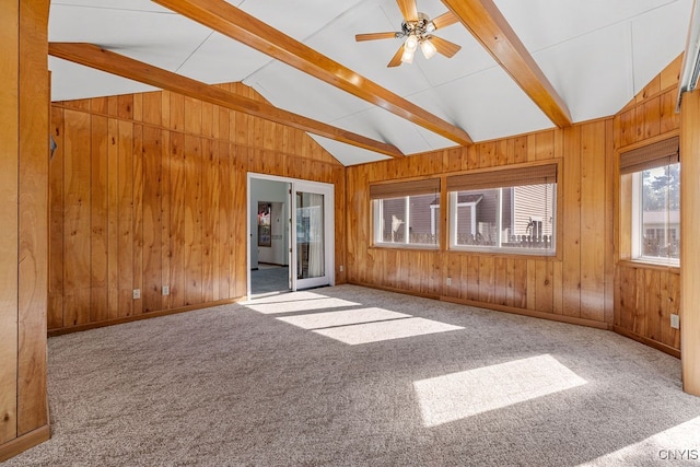 carpeted spare room with lofted ceiling with beams, ceiling fan, and wooden walls