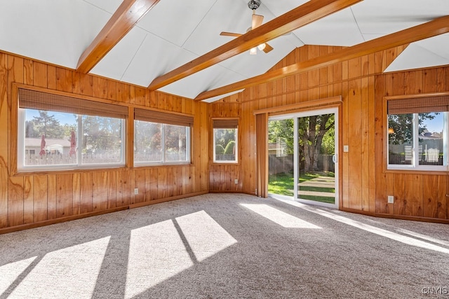 carpeted empty room with ceiling fan, wooden walls, and vaulted ceiling with beams