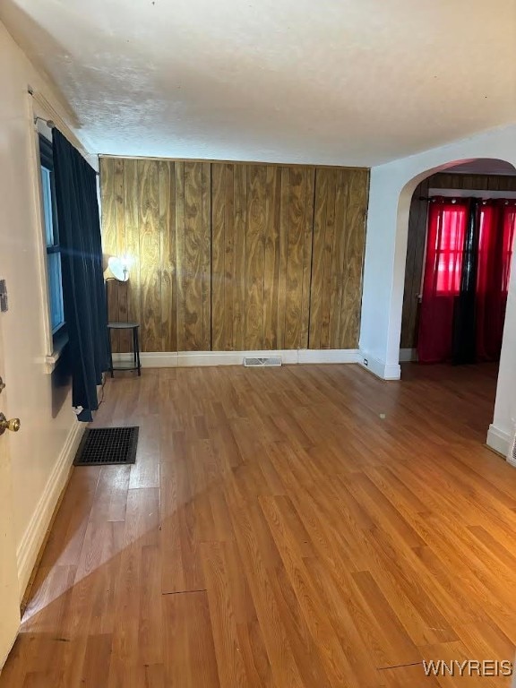 empty room featuring hardwood / wood-style flooring and wood walls