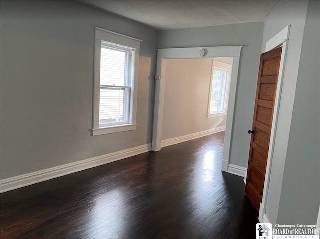 spare room with a textured ceiling and dark hardwood / wood-style floors