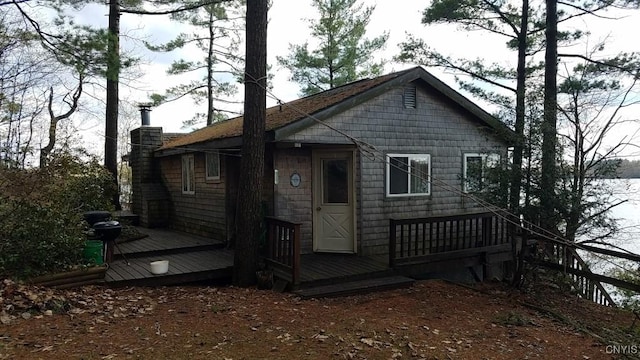 back of house with a wooden deck and a chimney