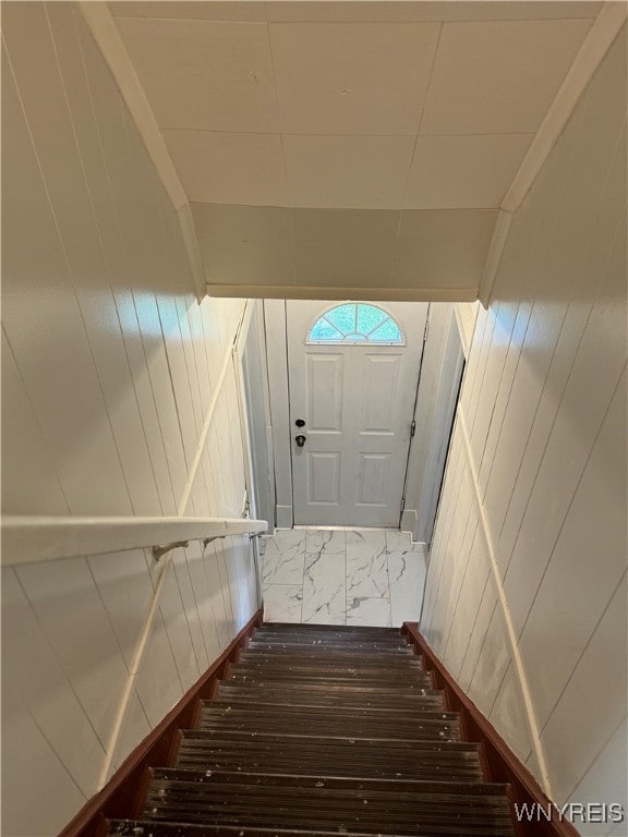 staircase with wood-type flooring and wood walls