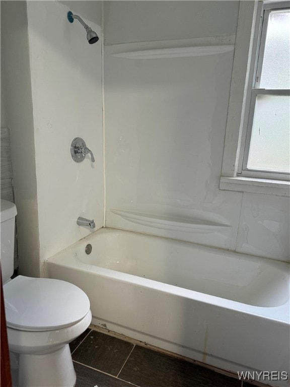 bathroom with toilet, plenty of natural light, and bathing tub / shower combination