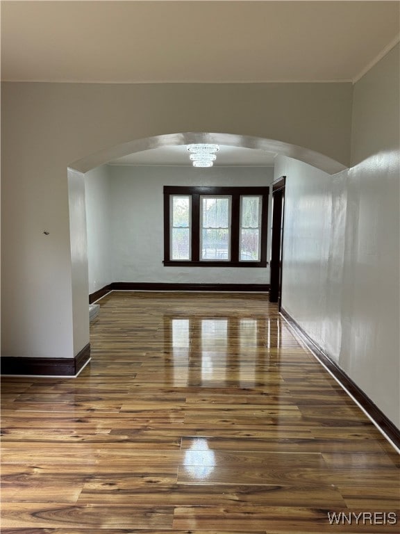 unfurnished room with wood-type flooring and an inviting chandelier