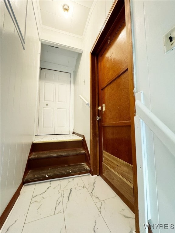 hall featuring ornamental molding and wood walls