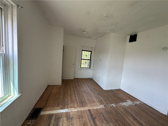 unfurnished room featuring dark wood-type flooring and a textured ceiling