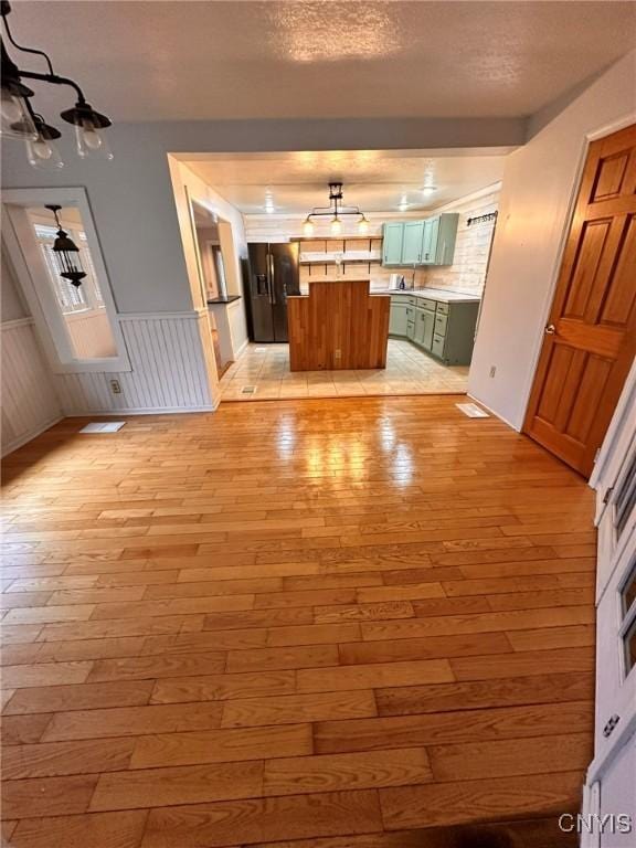 205 S James St, Wilna, NY 13619 - unfurnished living room featuring light wood-style floors, wainscoting, and a textured ceiling
