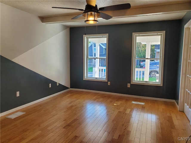 empty room with ceiling fan, vaulted ceiling, light hardwood / wood-style floors, and a textured ceiling