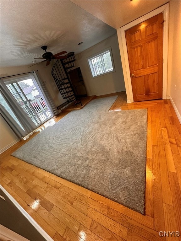 unfurnished living room featuring light wood-type flooring, ceiling fan, and a textured ceiling