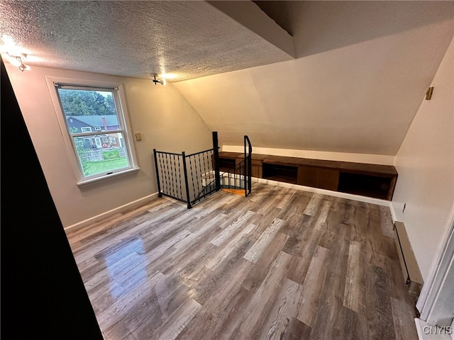 bonus room with a textured ceiling, vaulted ceiling, and hardwood / wood-style floors