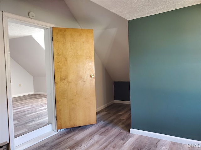 bonus room with a textured ceiling, hardwood / wood-style floors, and lofted ceiling