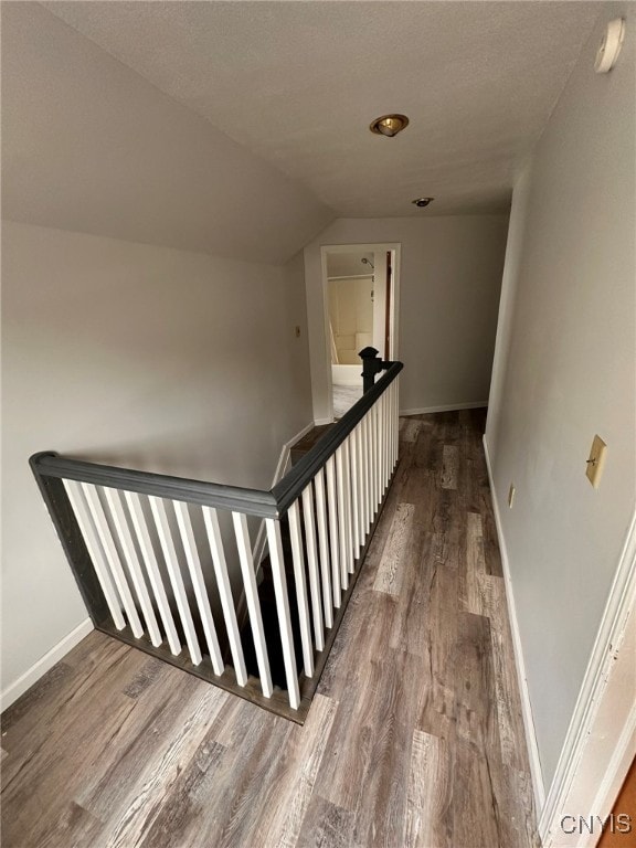 stairs with lofted ceiling, wood-type flooring, and a textured ceiling