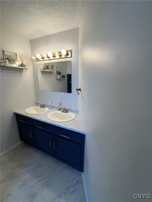 205 S James St, Wilna, NY 13619 - full bathroom featuring double vanity, a textured ceiling, marble finish floors, and baseboards