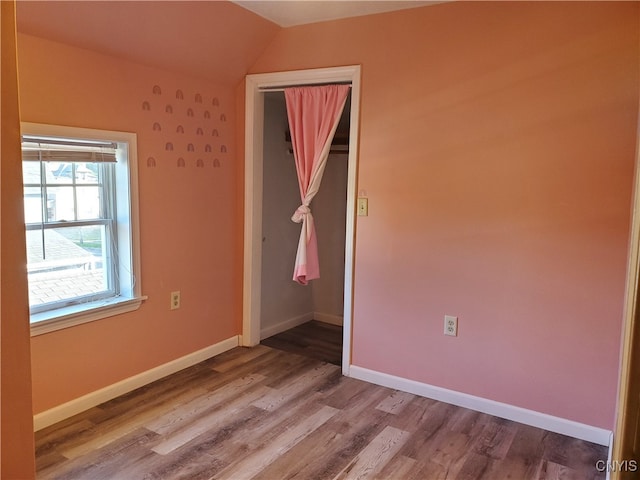 spare room with vaulted ceiling and hardwood / wood-style floors