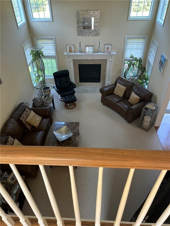 living room featuring a tiled fireplace, a wealth of natural light, and a towering ceiling