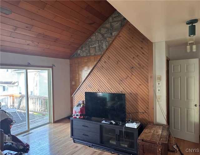 living room with wooden walls, vaulted ceiling, and light hardwood / wood-style floors