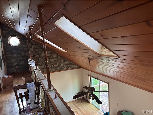 interior space with vaulted ceiling with skylight, hardwood / wood-style floors, wooden ceiling, and ceiling fan