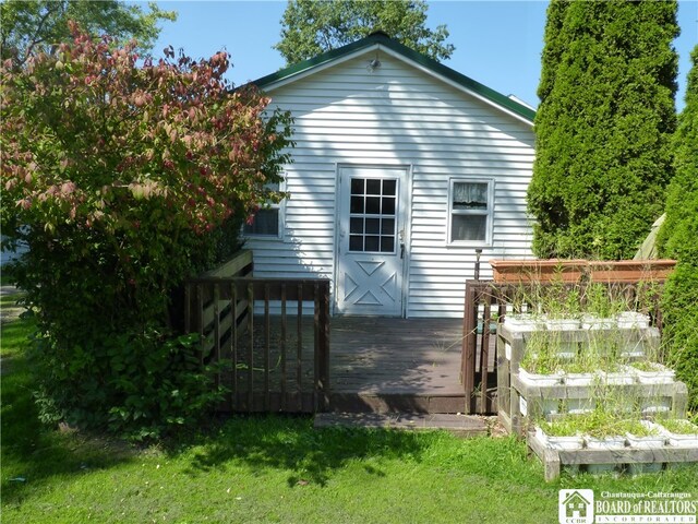 rear view of house featuring a wooden deck and a yard