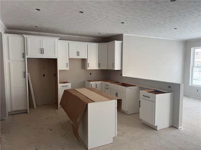 kitchen with white cabinetry, a center island, and a textured ceiling