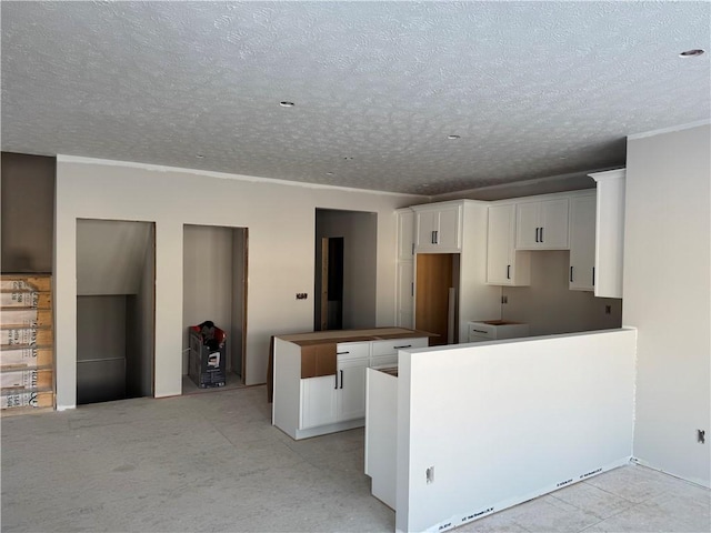 kitchen with ornamental molding, a textured ceiling, and white cabinets