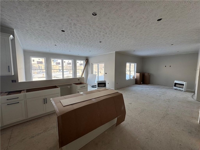 kitchen with white cabinetry, a kitchen island, and a textured ceiling