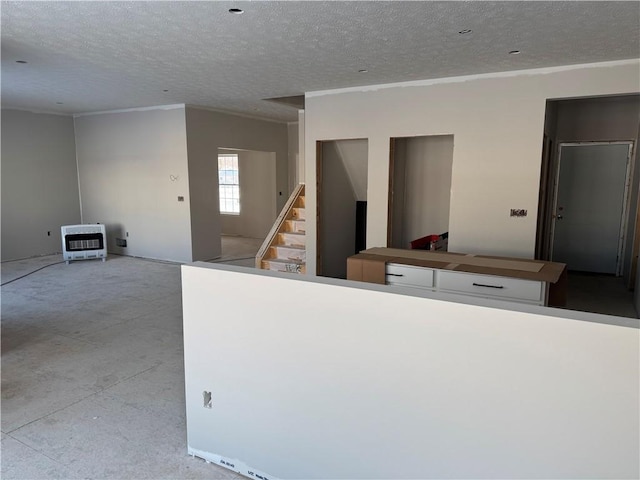 interior space featuring heating unit, white cabinets, ornamental molding, and a textured ceiling