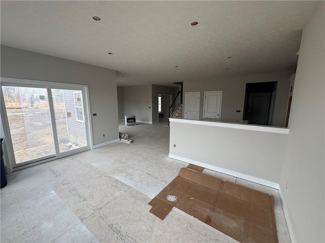 spare room with stairs, baseboards, and a textured ceiling