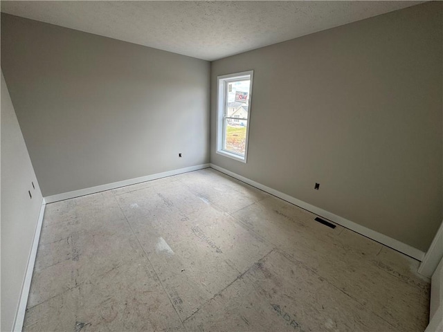 empty room featuring a textured ceiling and baseboards