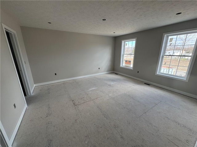 unfurnished room featuring visible vents, baseboards, and a textured ceiling
