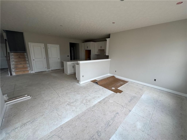 unfurnished living room with baseboards and a textured ceiling