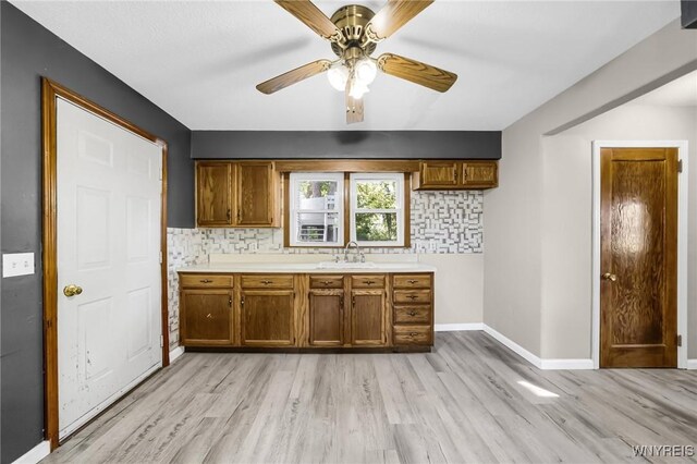 kitchen with light wood-type flooring, backsplash, sink, and ceiling fan