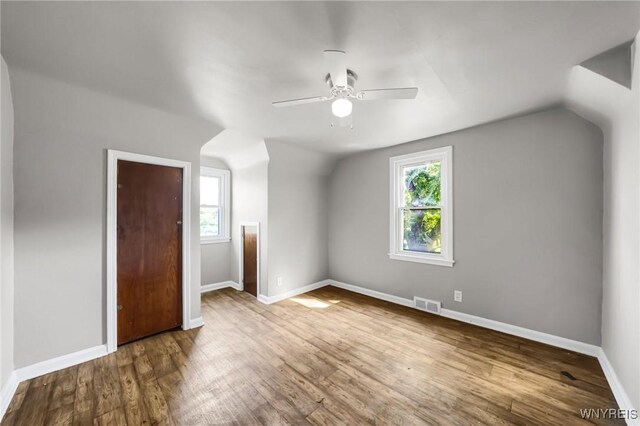 unfurnished bedroom featuring dark wood-type flooring, multiple windows, ceiling fan, and lofted ceiling