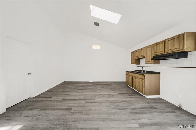 kitchen with light wood-type flooring, vaulted ceiling with skylight, and sink