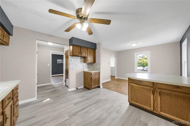 kitchen with light wood-type flooring, tasteful backsplash, and ceiling fan