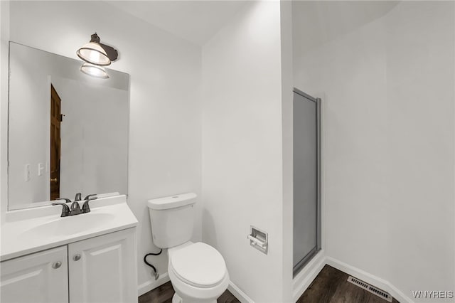 bathroom with an enclosed shower, hardwood / wood-style floors, toilet, and vanity